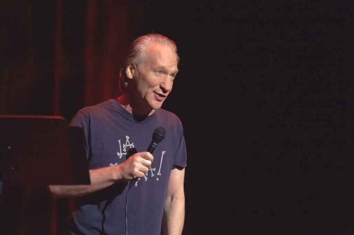 Bill Maher performing stand-up with a microphone on stage
